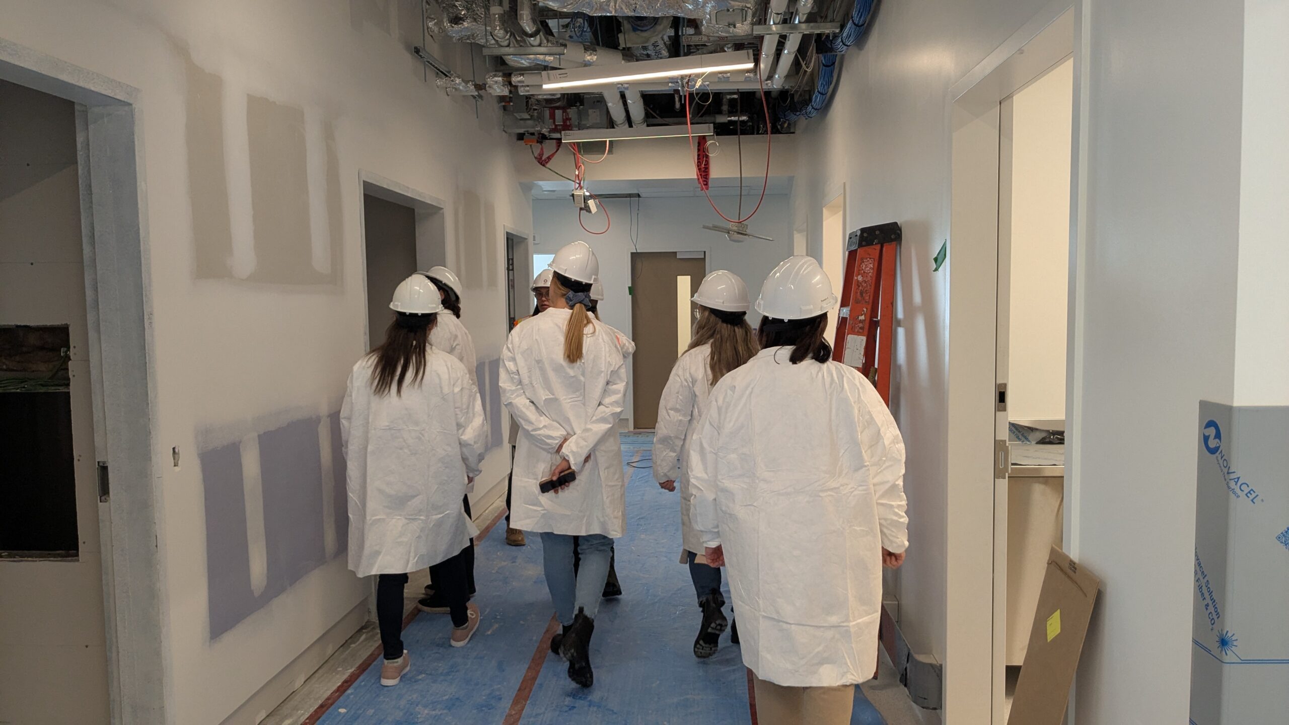 Groupe de personnes portant casque et protection de vêtements à l'intérieur du chantier du pavillon J
